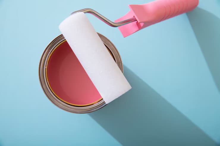 A paint roller is used to coat a can of paint, demonstrating a step in commercial painting techniques.