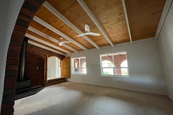 A room featuring a brick wall and a ceiling fan, showcasing an aluminum and metal painting on display.