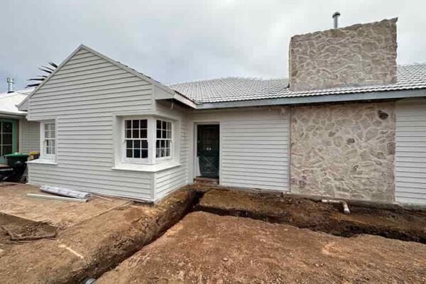 A construction site showing a house being built with dirt and sand for exterior service.