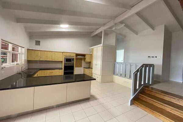 Interior view of a kitchen with a contemporary black countertop paired with classic white cabinets, creating a chic atmosphere.