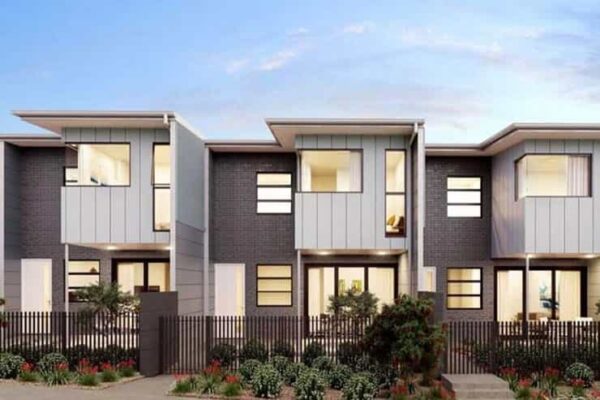 A three-story townhouse with a fence surrounding the property.