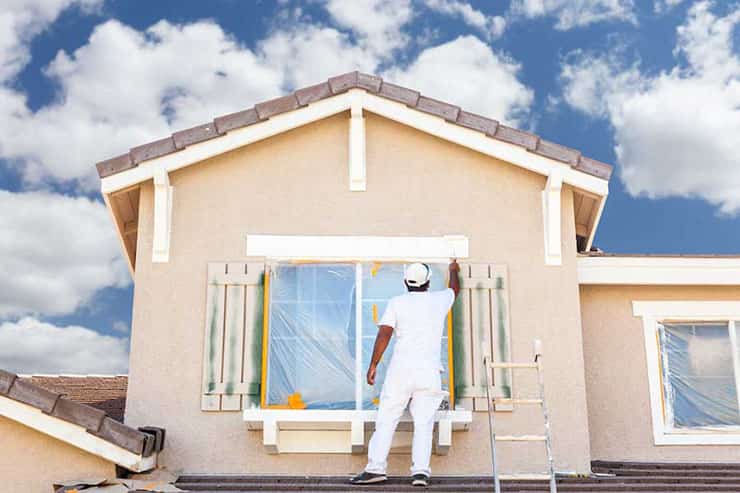 A man painting a window on a house, showcasing the process of render painting.