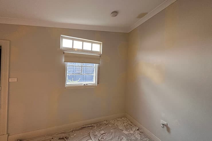 A vacant room with a window and a freshly painted wall, showcasing options for repainting in rental houses.